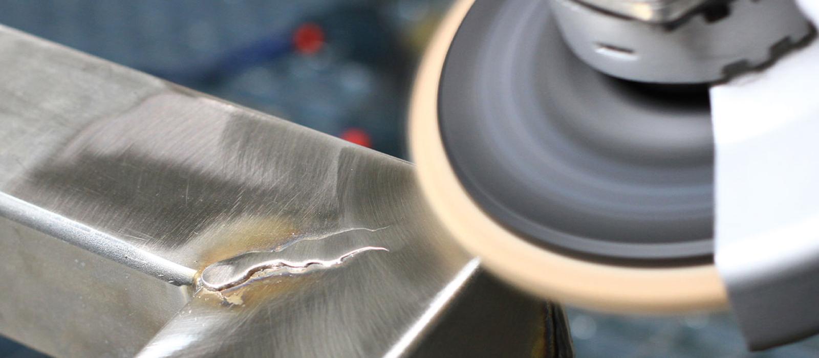 Bild på person som bearbetar svetsfog med en polernylonrondell